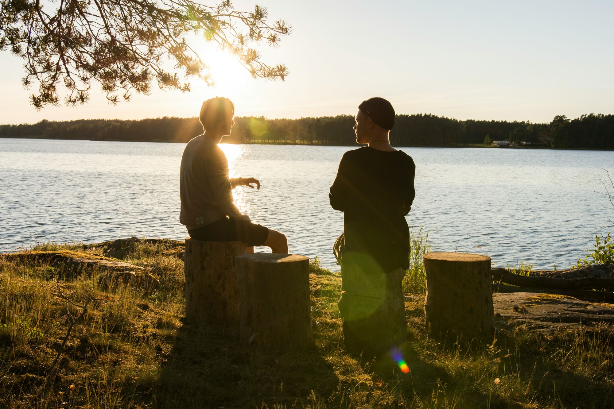 Two people talking by a lake at sunset